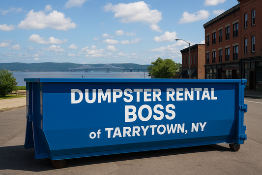 A large blue dumpster labeled “Dumpster Rental Boss of Tarrytown, NY” placed on a street with views of the Hudson River and Tappan Zee Bridge in the background.